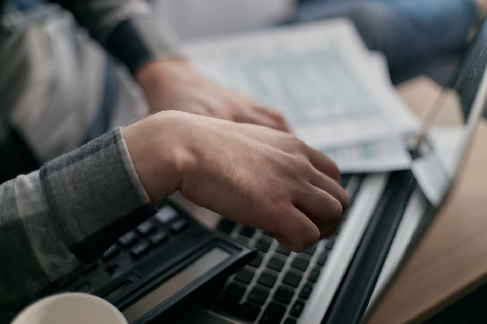 Tax forms, calculator and laptop laid out for end-of-year payroll clean-up