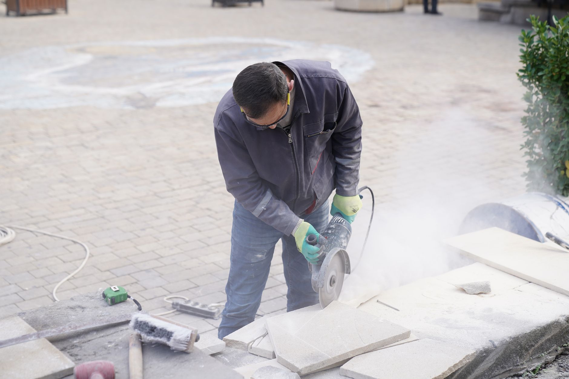 Tradie cutting stone outdoors through dust and grit at a worksite
