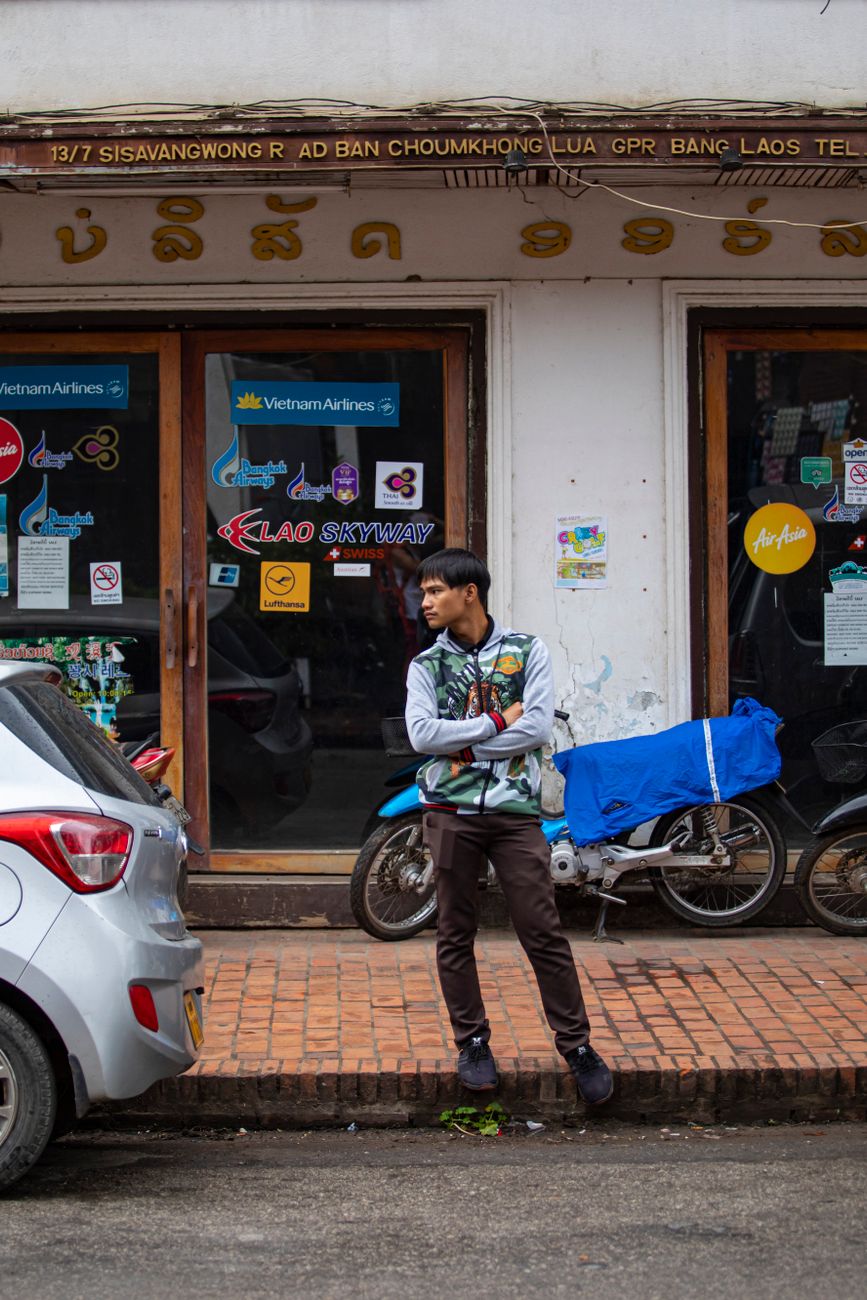 Traveller outside a Laos travel agency on a street lined with backpacker businesses