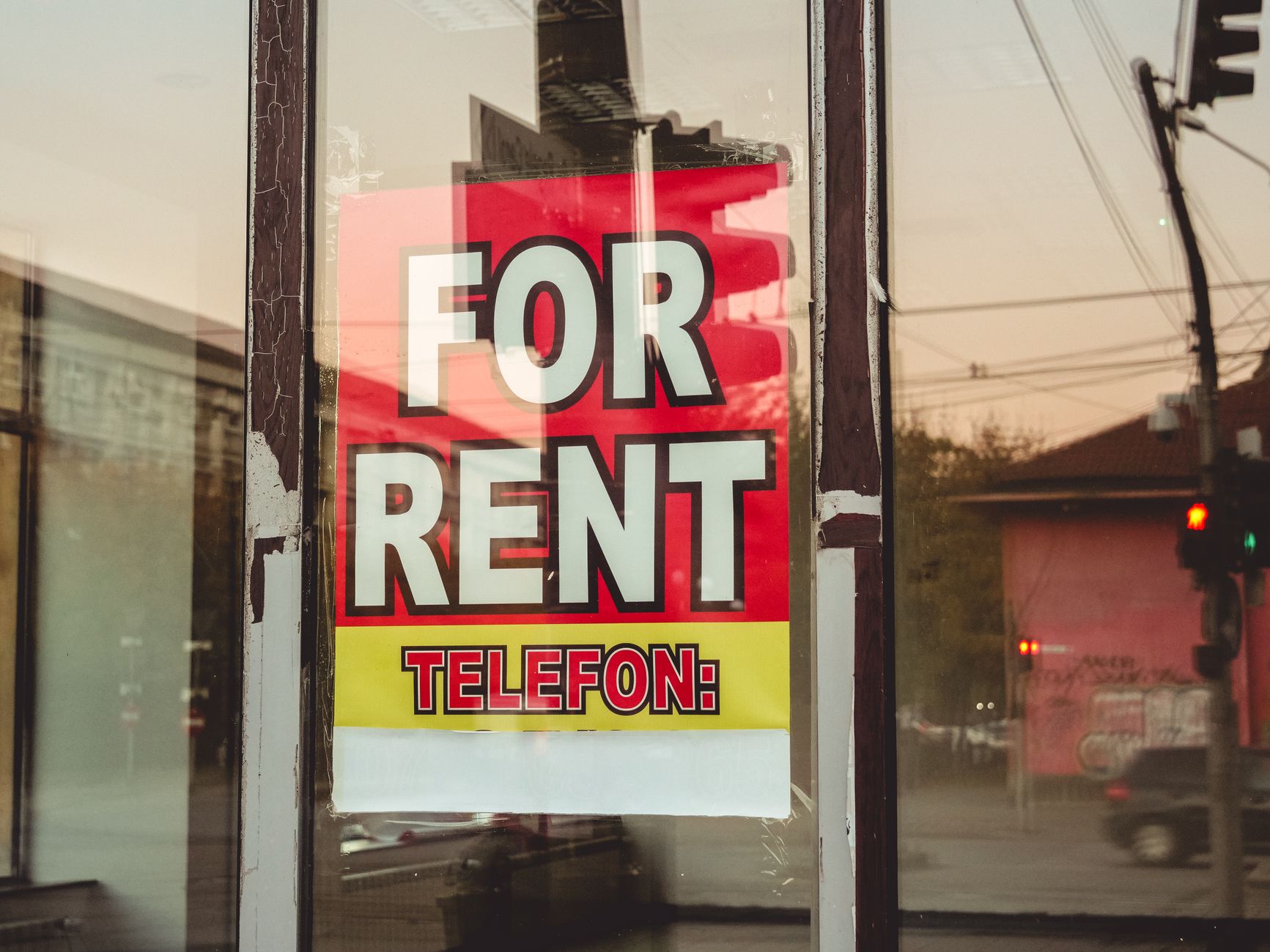 For-rent sign reflected over city buildings at sunset.