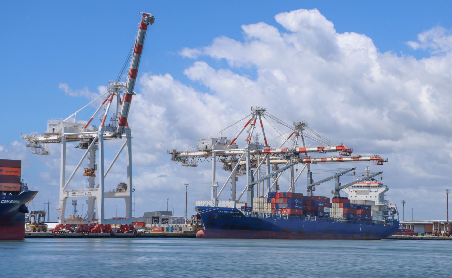 Container ship docked at Port of Brisbane under a cloudy sky.